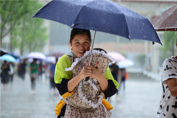 高考结束,考生父母冒雨来接孩子给考生拿行李的母亲,被困雨中雨中着急