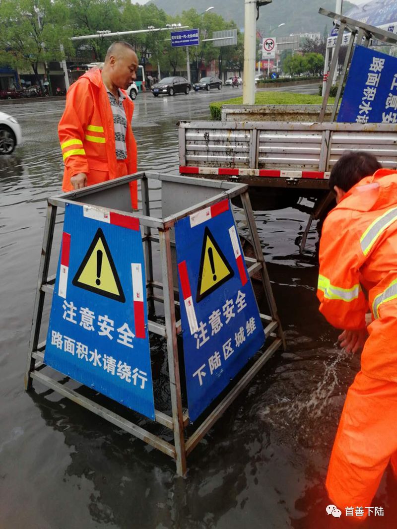 △ 在重积水路段,市政人员冒雨撬雨水井井盖,放置安全警示牌