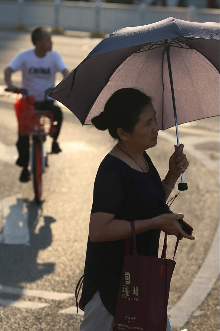 2019年6月26日,深圳深南东路,在阳光下打伞的女子.