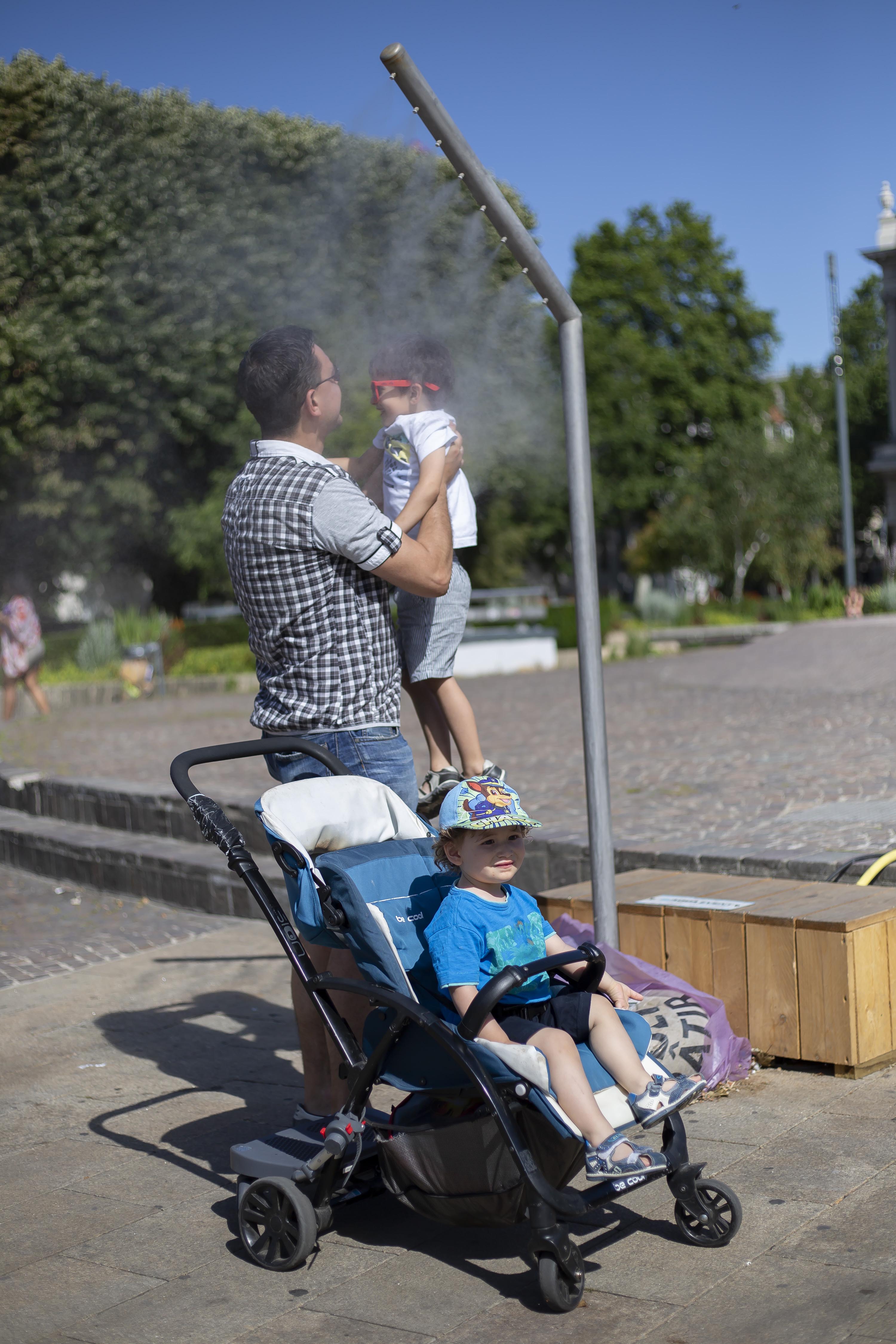 6月28日,在法国东部城市斯特拉斯堡,一个小女孩在喷泉旁戏水消暑.