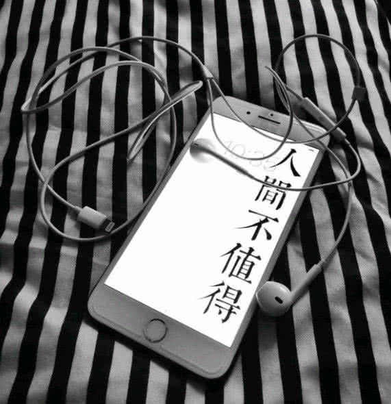 黑白鲜明的被子上放着一个手机,上面写着人间不值得,好像时时在提醒