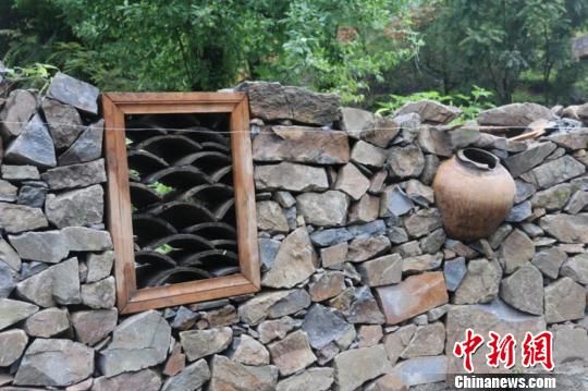 图为村民们不用的废旧陶罐成景观墙装饰. 李智谋 摄