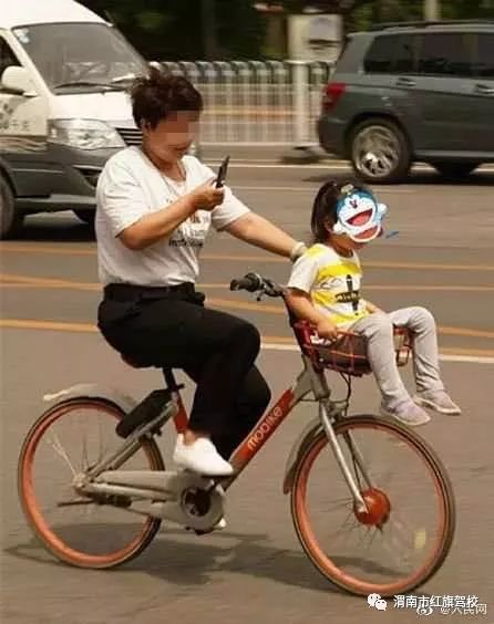 单手骑车,还玩手机,重点是车筐放着小朋友.