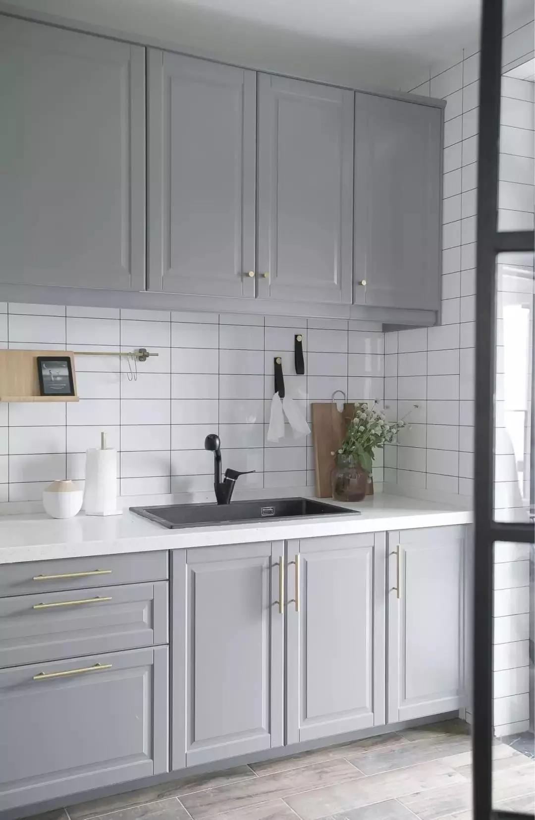厨房地面拼贴木纹砖,墙面采用文艺的白色瓷砖,灰色橱柜金色拉手