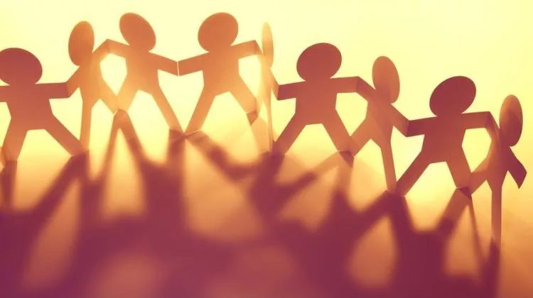 配图:地面上立着一群用剪纸做的小人,他们并排"站着",手拉着手(图片