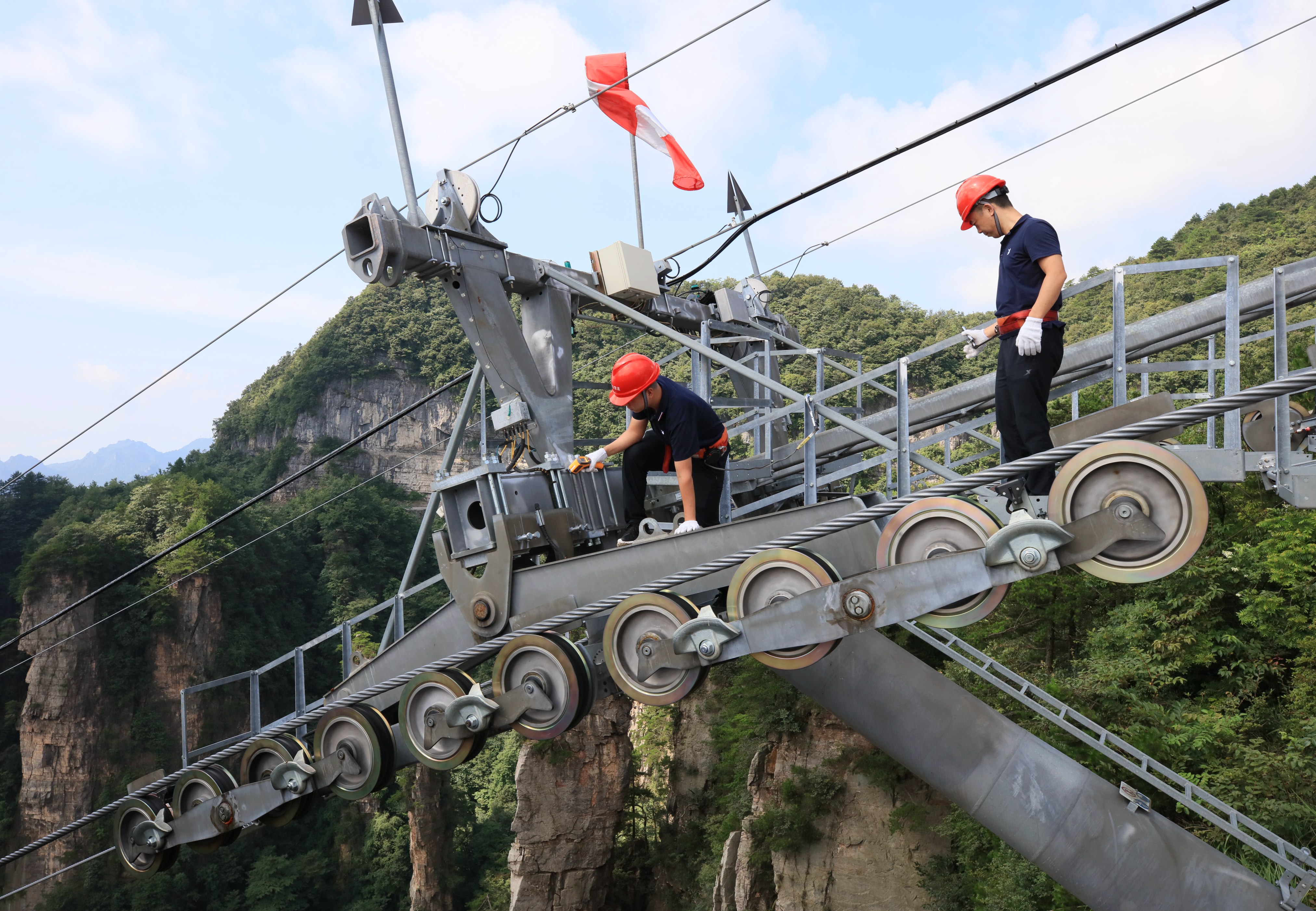 7月31日,张家界武陵源景区天子山索道工作人员在高空索道支架上对运行