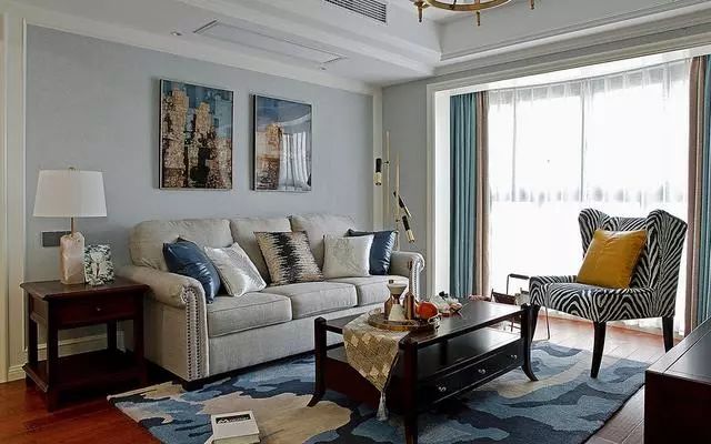 客厅墙面刷蓝灰色漆,搭配浅色沙发,深色茶几电视柜,结合抽象派地毯