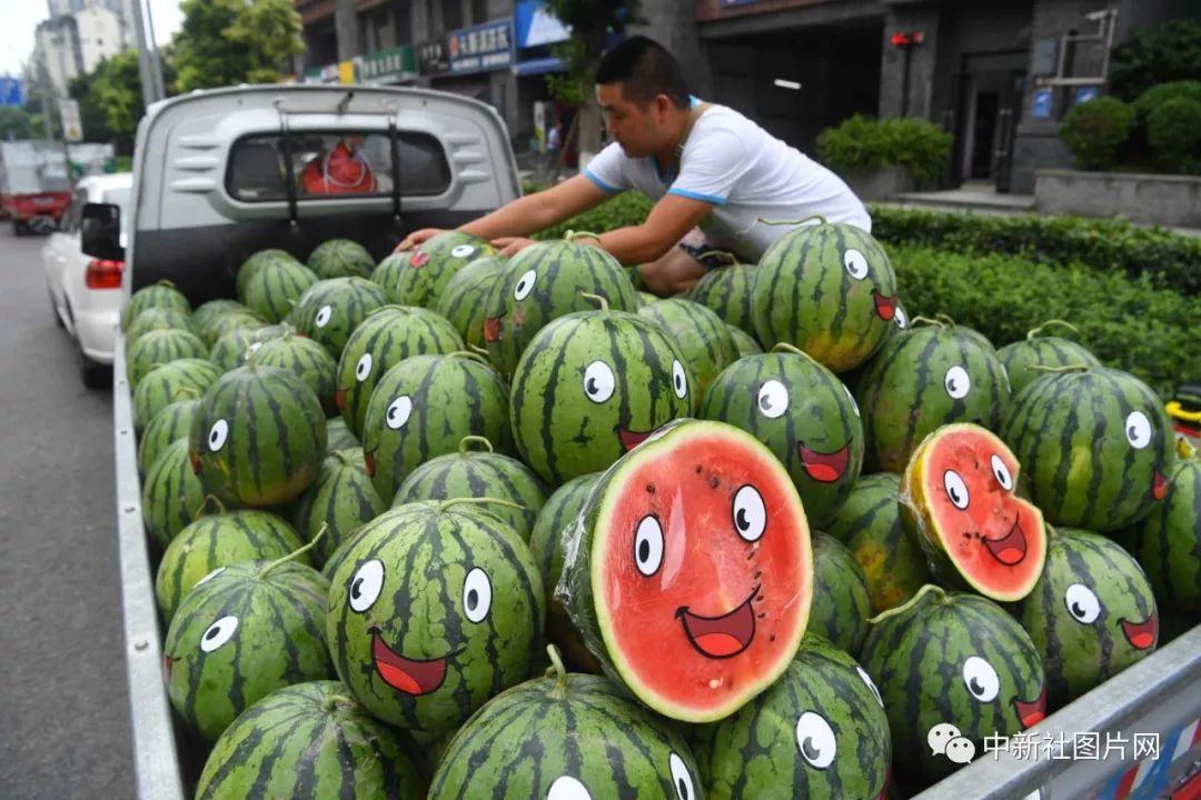 7月7日,重庆街头一商贩将西瓜贴上笑脸图案,吸引顾客.