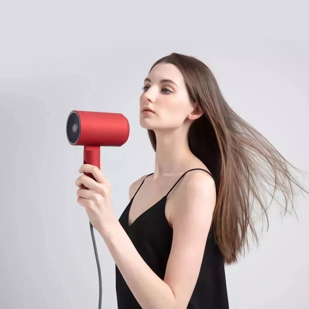 一位女士模特拿着吹风机吹着自己的头发美妆时尚素材设计