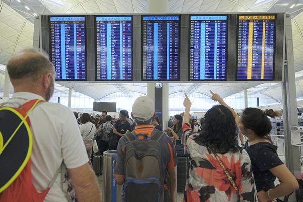 8月14日,旅客在香港国际机场航班动态显示屏上查看航班动态.