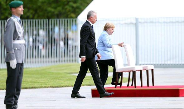 默克尔连续3次颤抖后，坐着和外宾听国歌