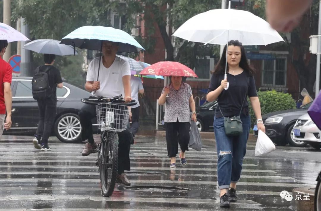 西城区三里河东路,市民们撑起雨伞冒雨走在上班路上.