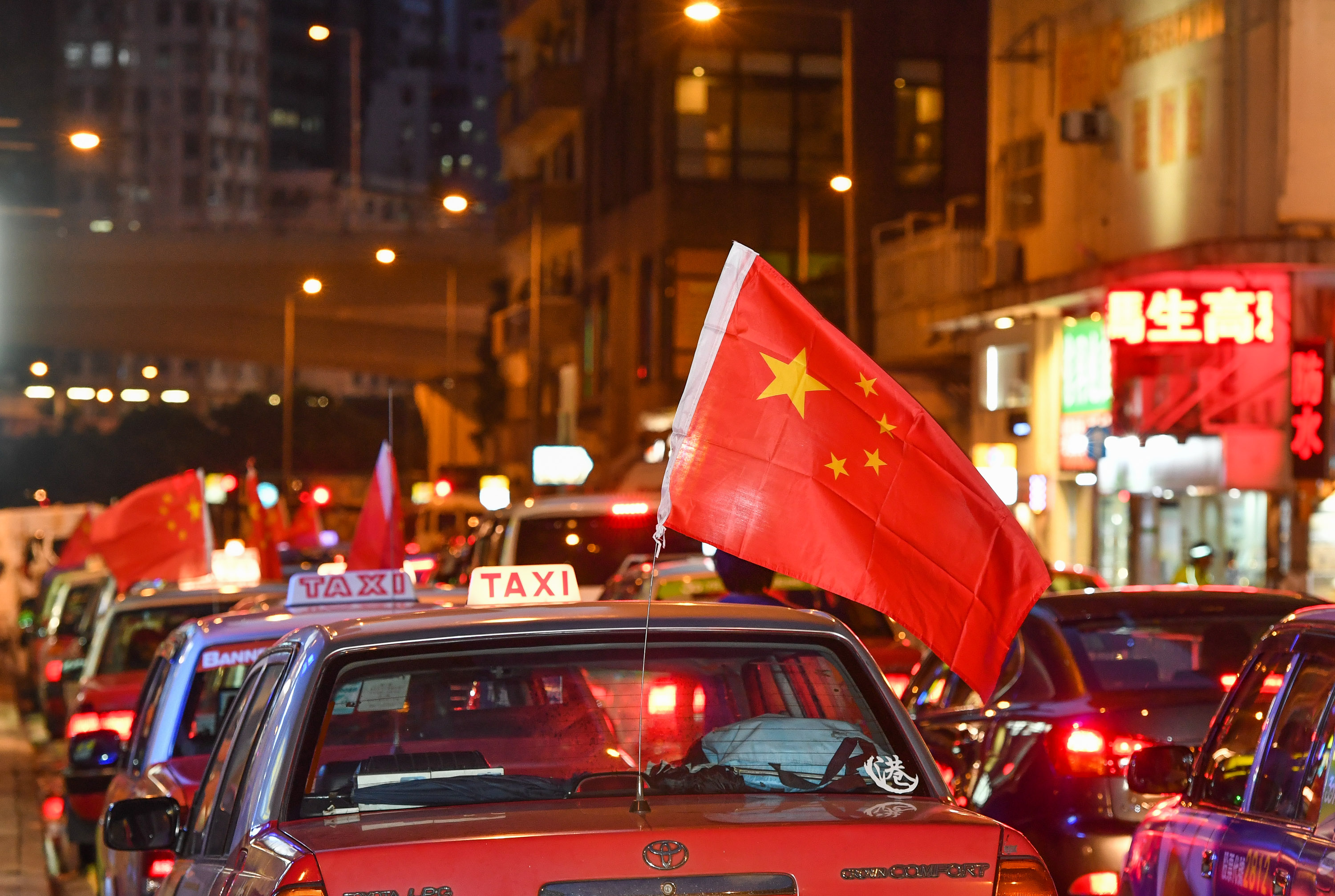 8月23日,从港岛筲箕湾出发的张挂中国国旗的出租车行驶在街道上.