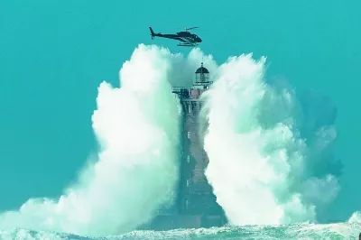 (法国布列塔尼海岸,巨浪裹挟着灯塔,险些将直升机吞没.)