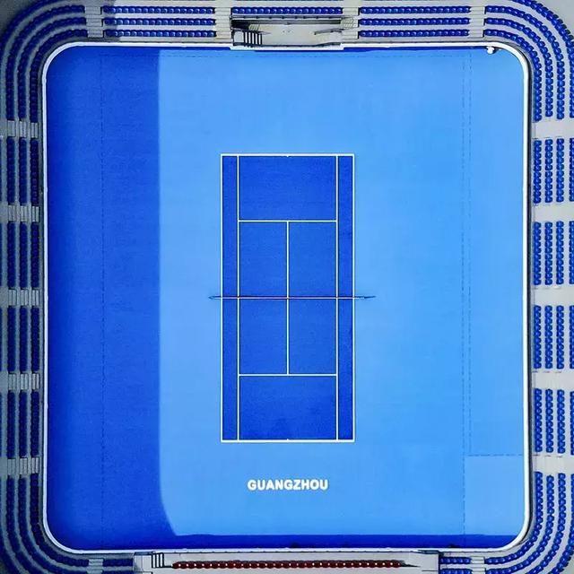 蔚蓝色的露天网球场被白色外围建筑环绕,空中俯视就像一颗璀璨的蓝