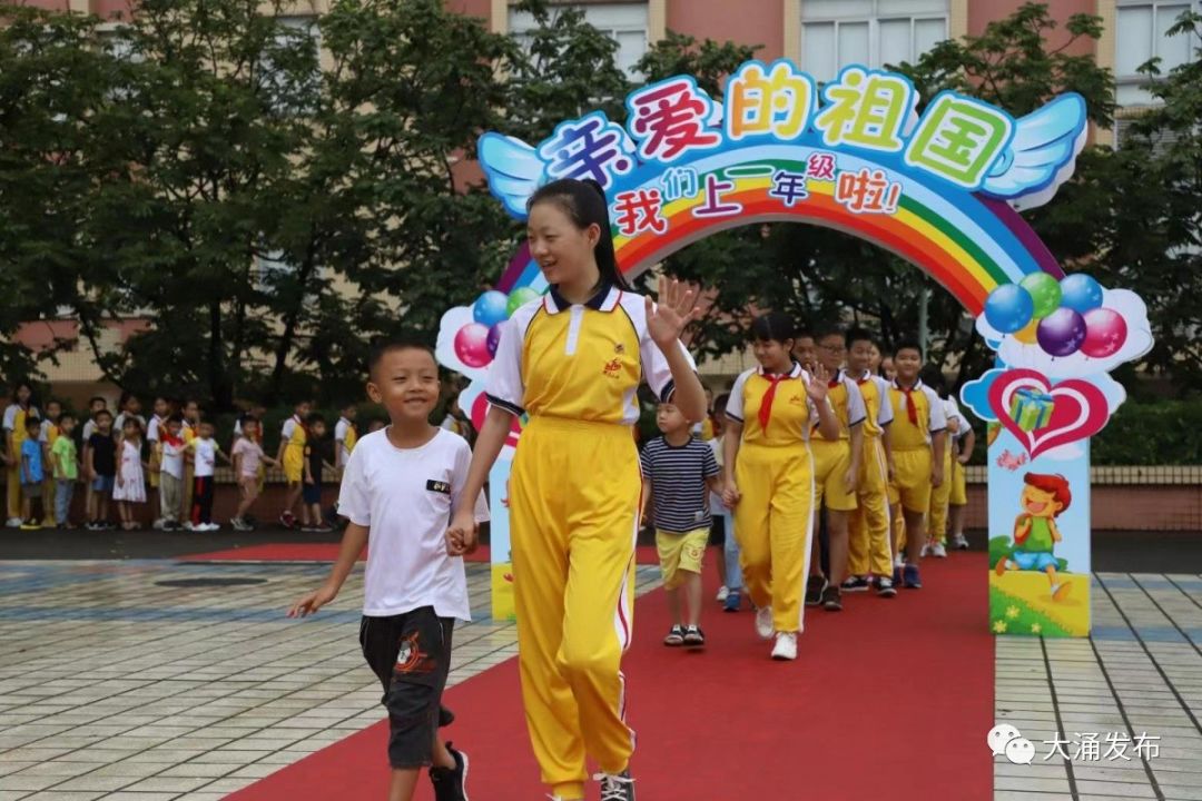 六年级的哥哥姐姐们 带领着一年级的小朋友走过红地毯, 通过入学门