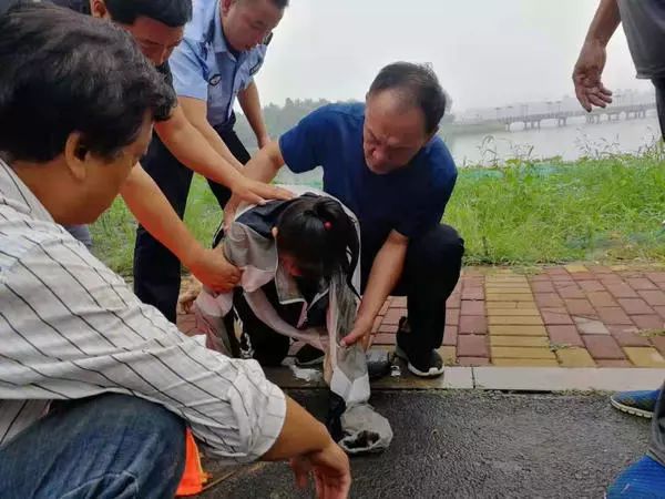 随后从女孩背后抱着她游向岸边.