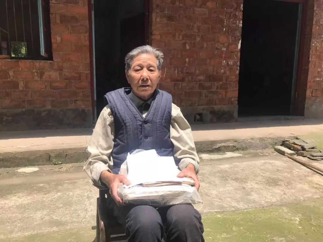 90岁的熊善初老人怀抱着常德细菌战受害者名册及个人陈述书等资料。他把