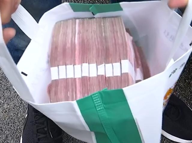 记者看到,这是一个银行的手提袋,里面装满了百元大钞,每10叠为一捆,一