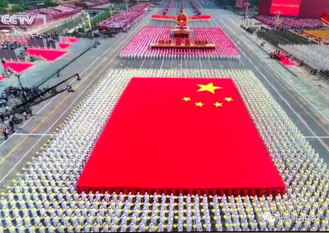 走到街上,群众在争着买国旗插门口,走到路上,5岁孩童在唱五星红旗迎风