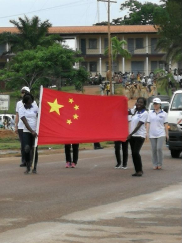 三八妇女节时,姆巴尔玛尤市市民举着中国国旗游行.