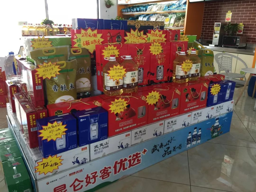 在加油站站,便利店主管精心装扮着非油堆头,堆头由酸奶,大米,牛奶等