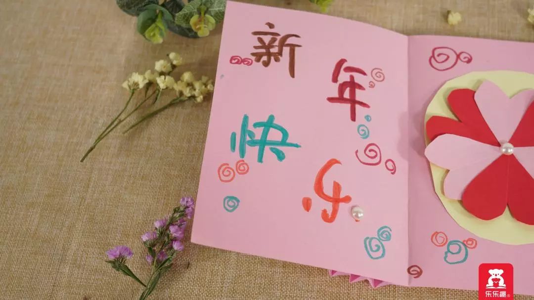 4,在贺卡内部写上新年快乐的字样,用各色水彩笔和珍珠亮片进行装饰