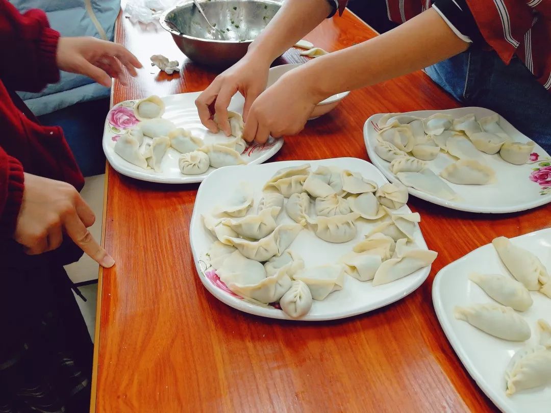 是个饺子沾水绕边饺子皮一合,一捏一折左手摊着一张饺子皮,右手拿勺挖