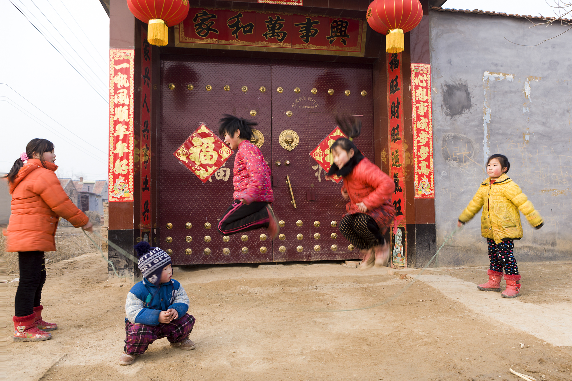 过年了,农村的小姑娘穿上漂亮的红衣服,在家门口欢乐地跳绳