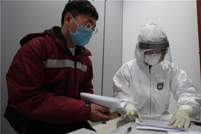 检测中心工作人员身穿防护服,头戴护目镜,按照生物安全三级实验室的