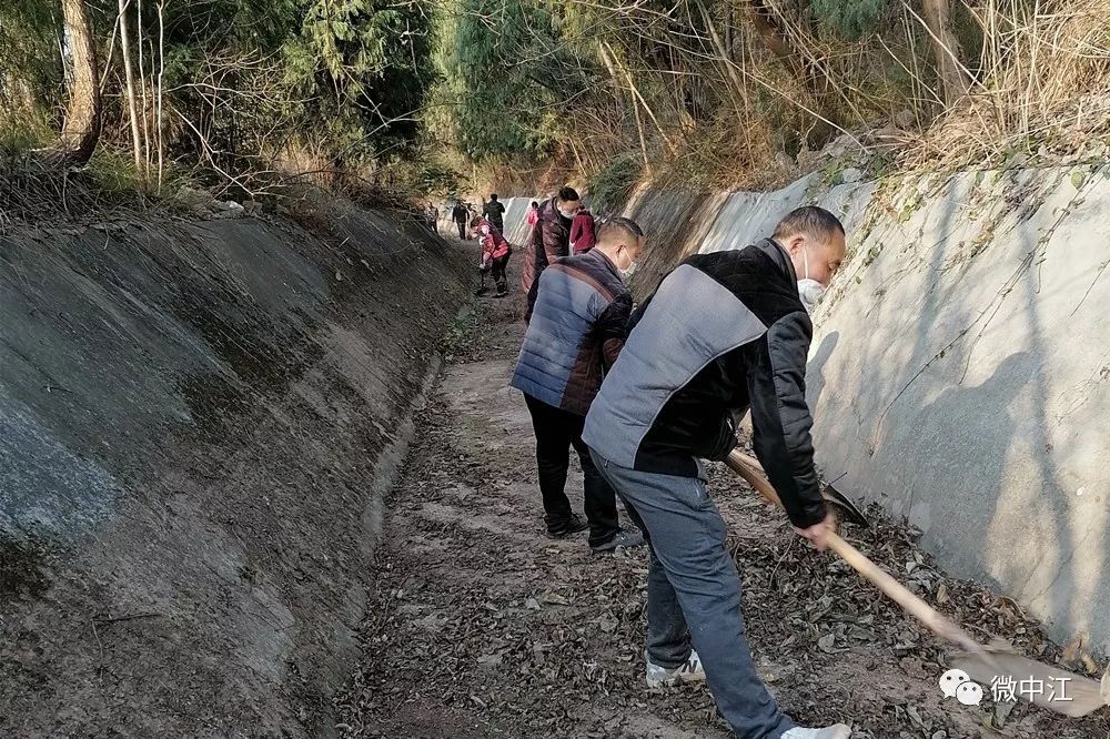 "中江县永太镇石狮村村文书谢小勇对正在黄山支渠除淤的贫困户阳运元