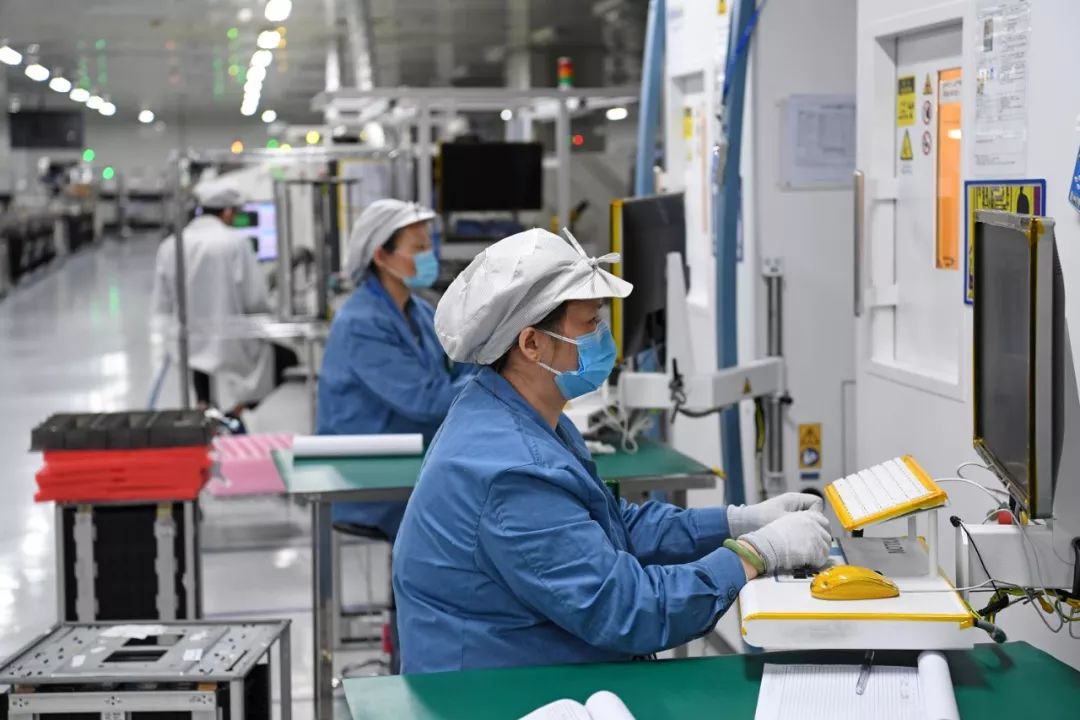 在位于深圳市龙岗区的海能达通信有限公司,工人们戴着口罩在生产车间
