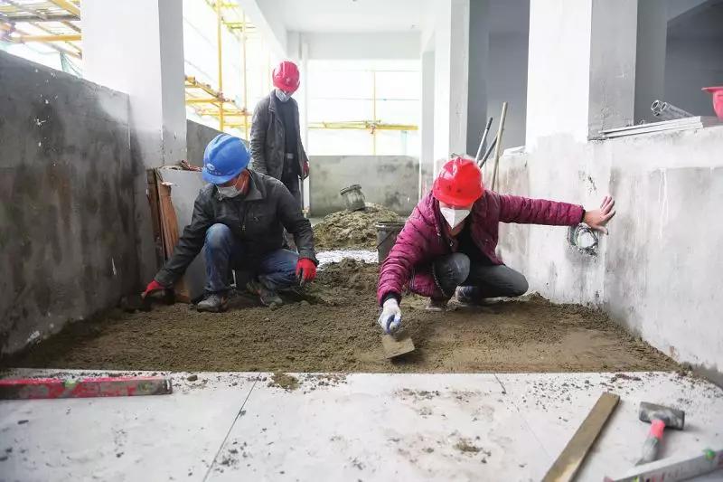 当天,项目施工现场,施工人员正在进行室内装修施工,包括室内墙体刮白