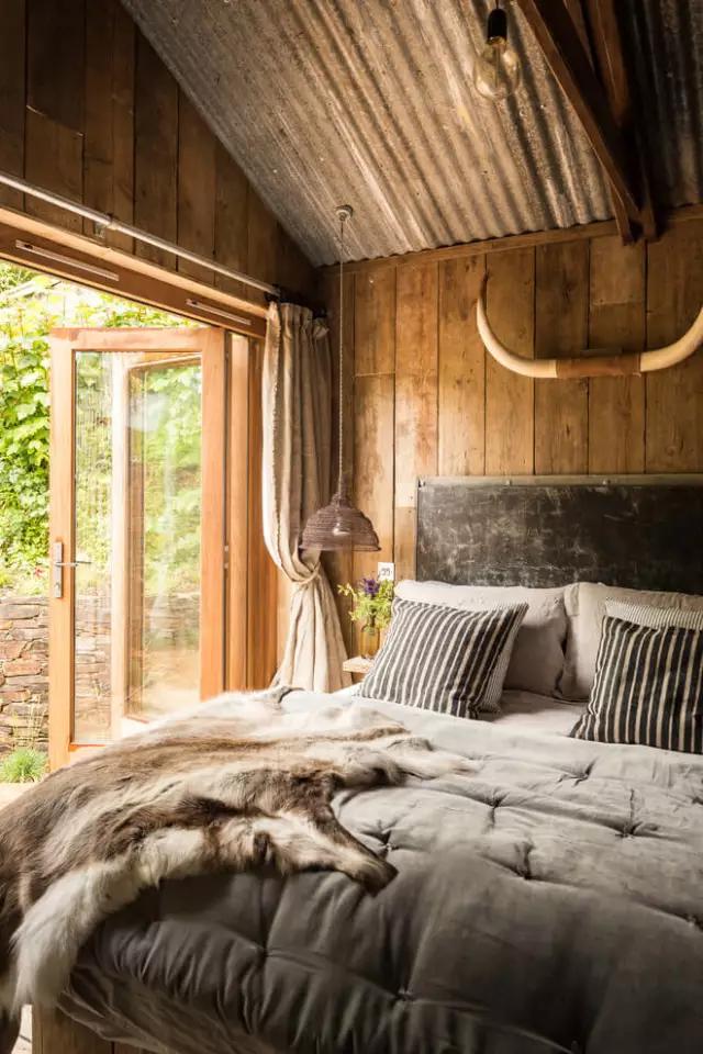 房间的墙面通体铺贴的老木头,卧室的床头用一对牛角作为装饰.