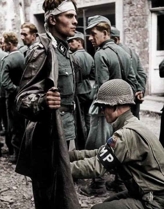 二,1944年,一名被俘的党卫军士兵一脸不情愿地被美军士兵搜身,虽然很