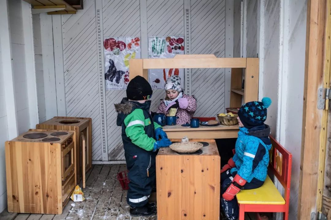 学前班的男孩和女孩在室外的玩具厨房里玩耍.
