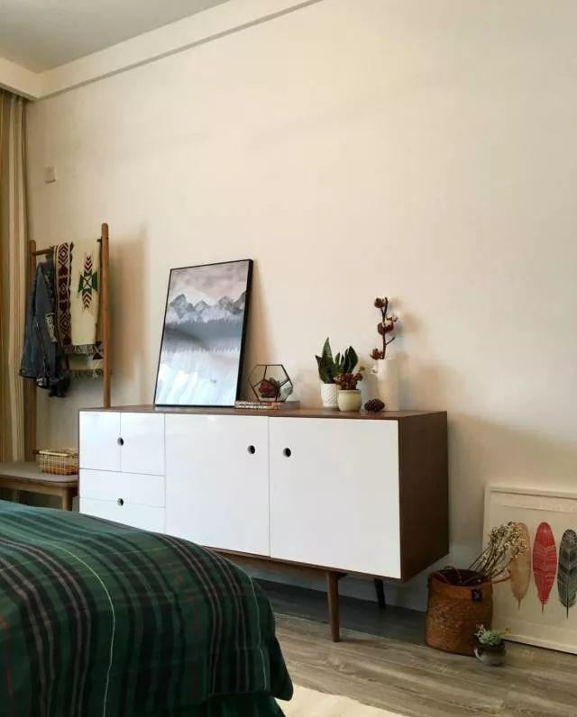 床尾放置一张成品矮柜增添卧室收纳空间,装饰画结合小盆栽,让空间
