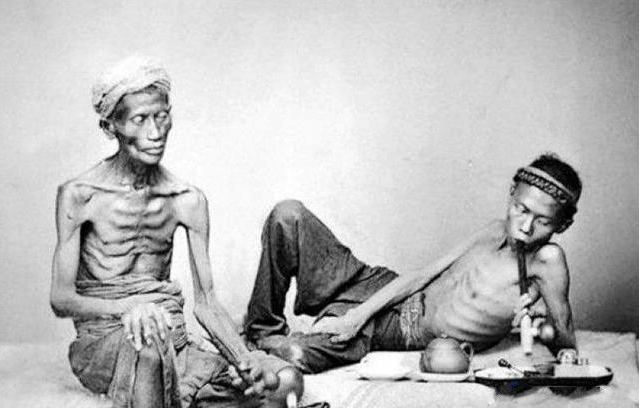 民国初期,两个骨瘦如柴的苦力男人在抽鸦片.