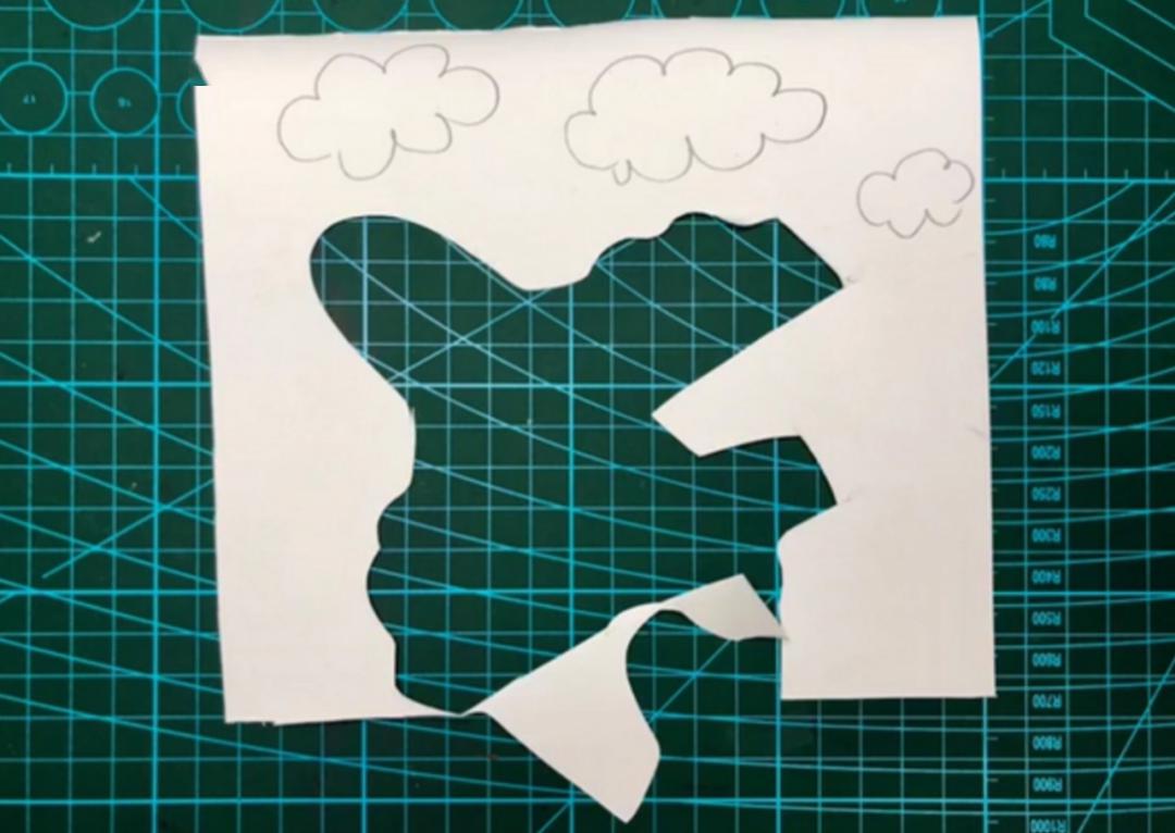 步骤三:在剩余的白色卡纸上画上白云并沿轮廓剪下