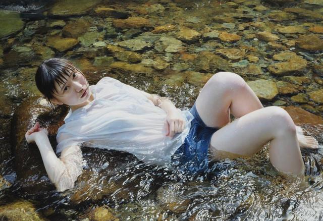 这是在一个水流的场景中,一位浸泡在清澈透明的水里面的湿透女子.