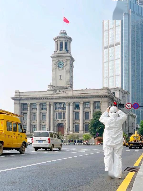 武汉江汉关大楼前,一名武汉市民穿着防护服,来纪念这个特殊的日子