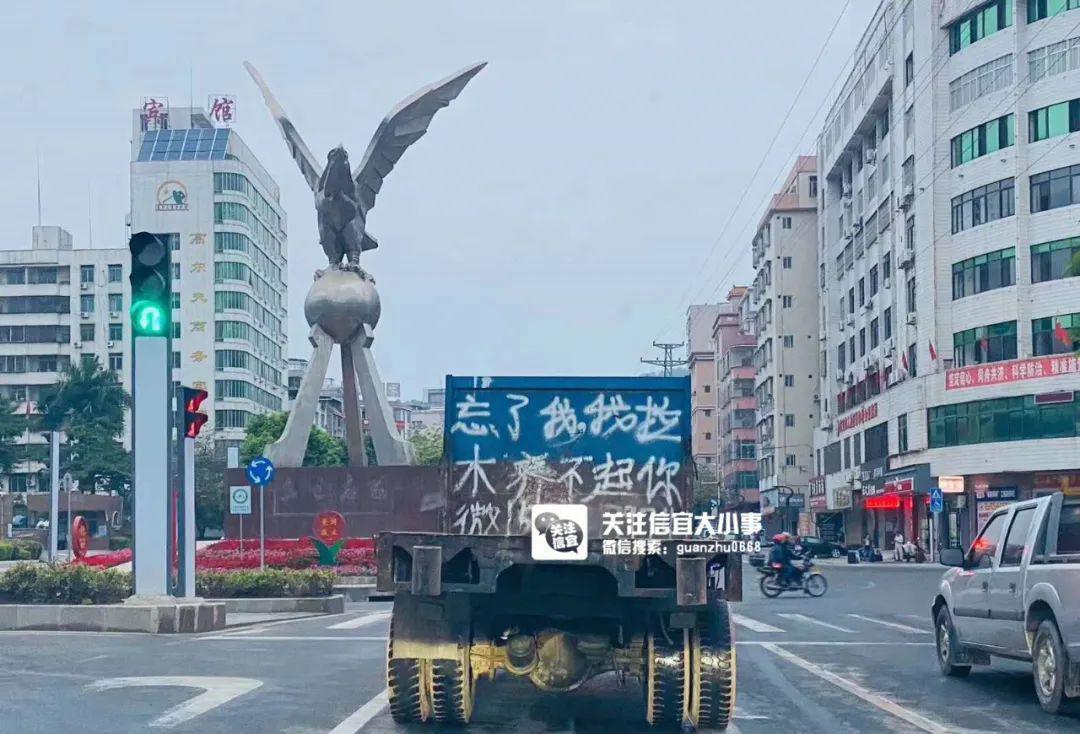一辆行驶在信宜飞鹰环岛的货车尾厢上写着"忘了我,我拉木养不起你