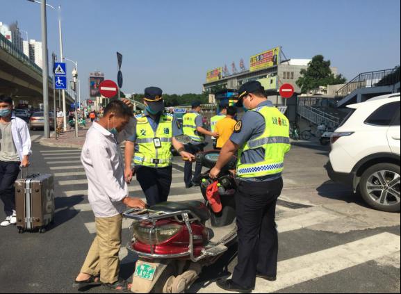图为执法人员对两轮电动自行车驾驶员进行教育劝导