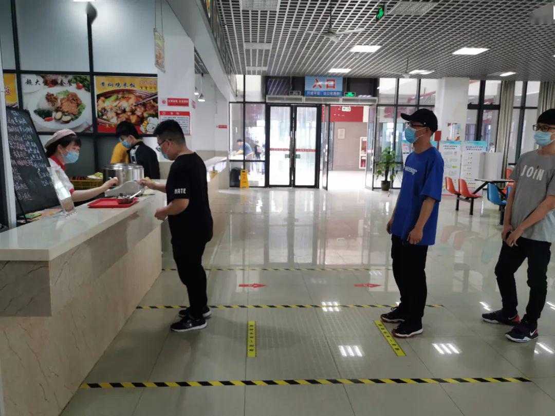 只见同学们保持秩序逐一进入食堂,自觉保持安全距离在各窗口排队取餐