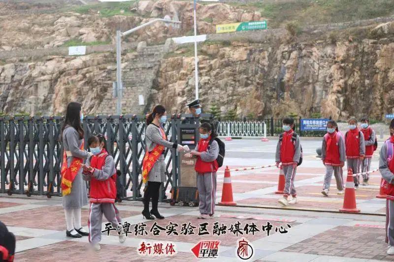 平潭澳前中心小学老师给入校学生进行手部消毒和测温平潭城关小学老师