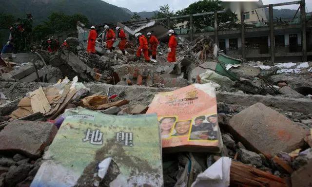 北川县城,北川中学学生们的课本散落在废墟上,救援人员正在废墟上