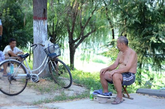 光膀子的小城,甭管是坐在地摊撸串喝酒的小伙子,还是坐在滨河公园的老