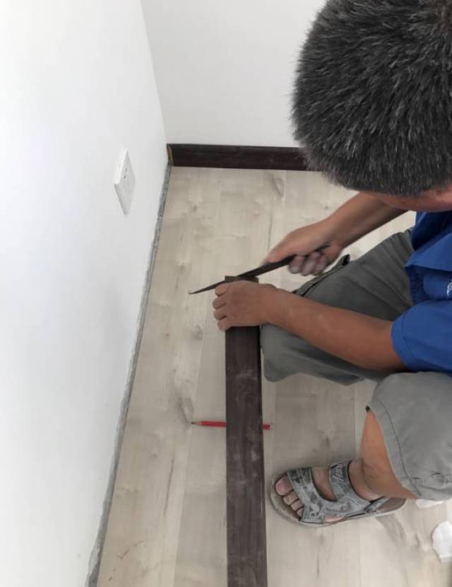 量,切,钻,装,新象朱师傅为了安装不出差错,一边用手扶住实木踢脚线
