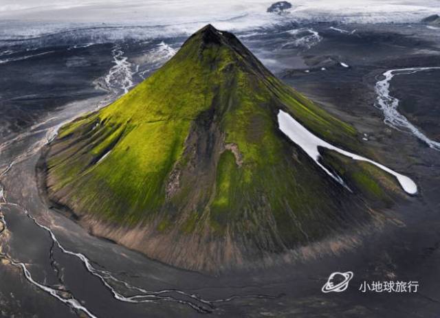 黑沙滩上,冰岛绿火山,呈现完美的锥形,河流流过,如丝带.