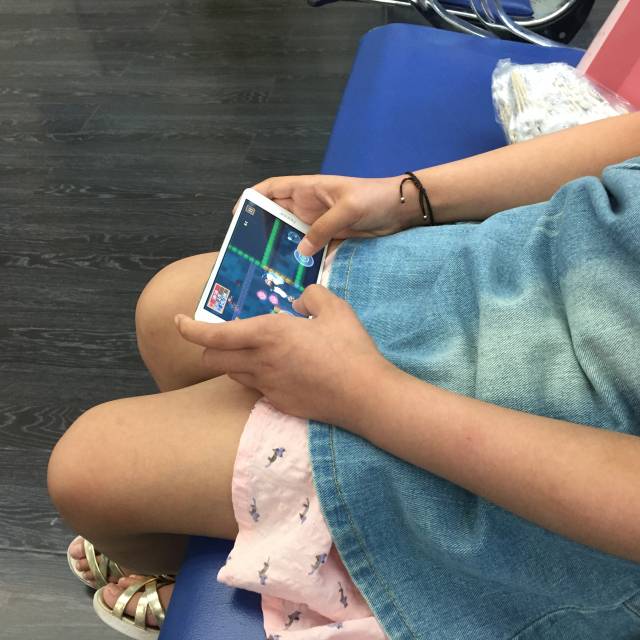 赵凯瑞(化名)在等待妈妈办理出院手续时一人玩着游戏.张笑晨 摄